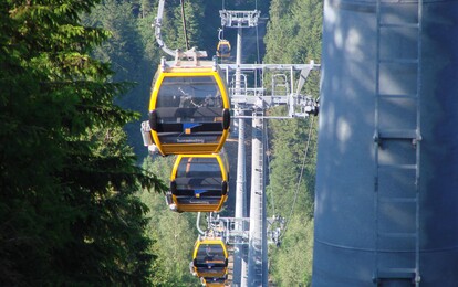 Die Gondelbahn mit mehreren Gondeln am steilen Hang.
