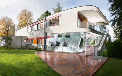Ein Designer-Haus mit Flachdach und vielen Fenstern umgeben von Bäumen.