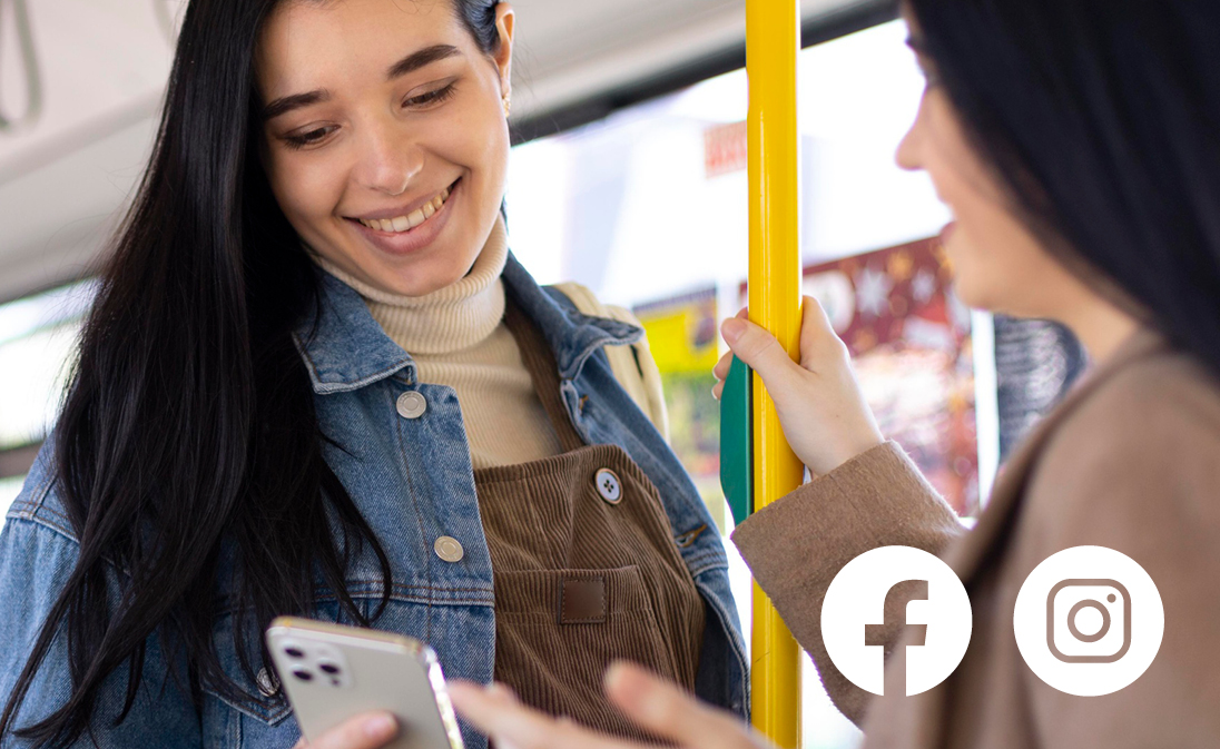 Eine Frau im Gespräch mit einer anderen Frau im Bus und sie gucken aufs Handy.